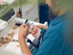 Crop senior male technician fixing jaw dentures in articulator