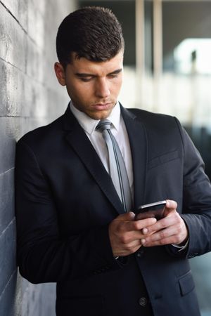 Portrait of man with blue eyes in suit and tie checking phone