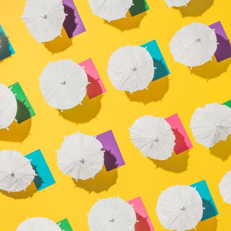 Pattern of sun umbrellas and multicolored towels in rows on yellow