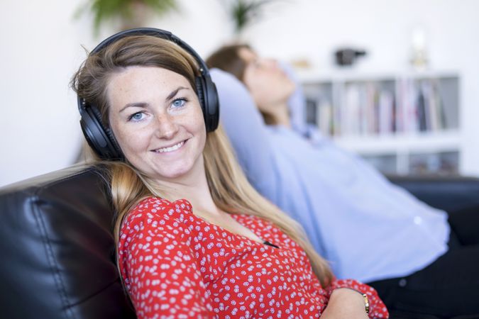 Woman looking at camera while friend relaxes on couch