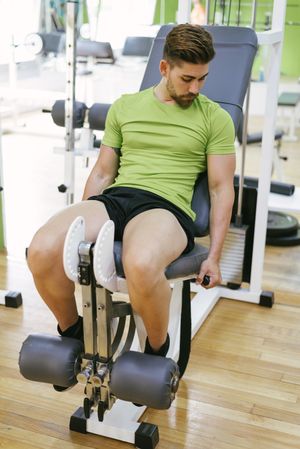 Male in green t-shirt working out on leg machine