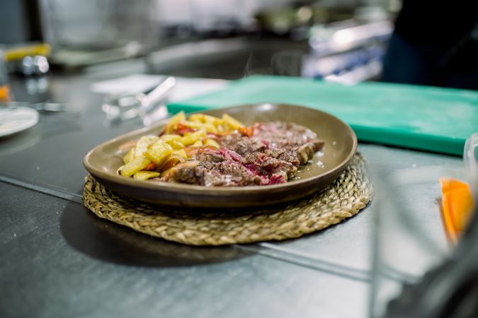 Delicious meal with meat and fried chips on table in kitchen