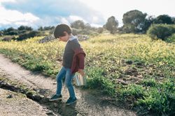 Kid with bucket walking on rural road