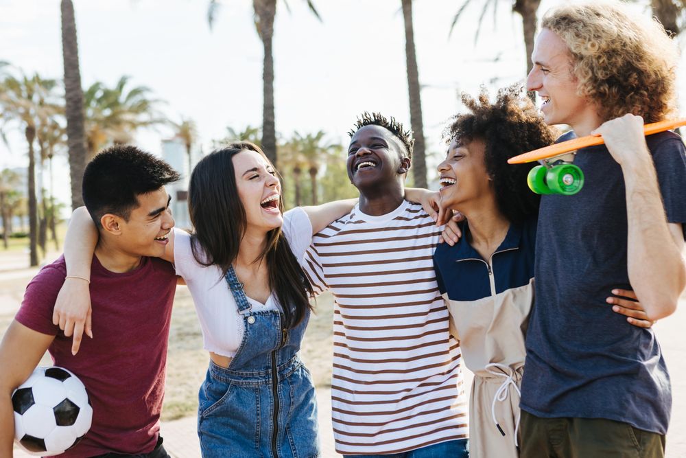 Happy friends from diverse cultures laughing and having fun at public park