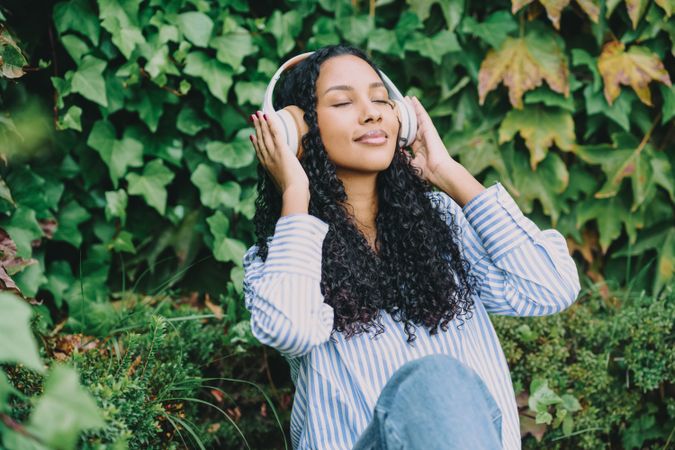 A Relaxing Woman Who Is Enjoying Uplifting Music While Surrounded by Nature with Headphones