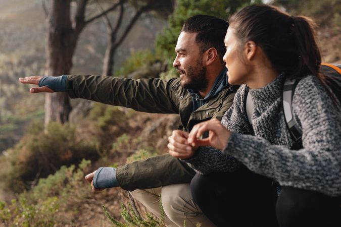 Man pointing at view while resting on a hike with girlfriend