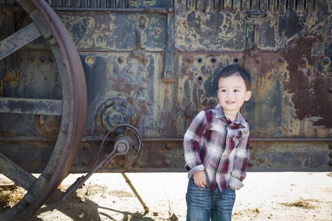 Young Biracial Boy Having Fun Near Antique Machinery