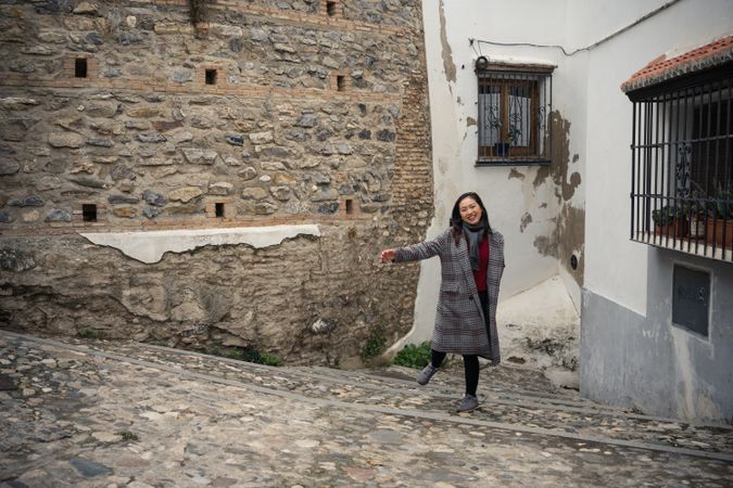 Asian female on aged cobblestone steps in city alley