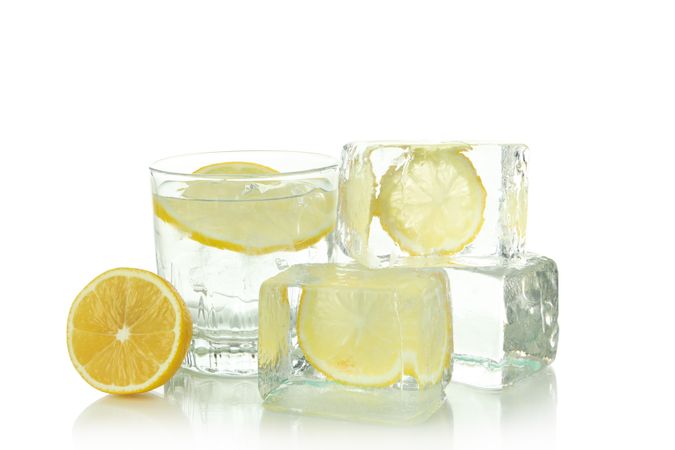 Square clear ice cubes with lemon slices, with glass of water