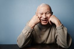 Smiling older man sitting at the table and looking at camera