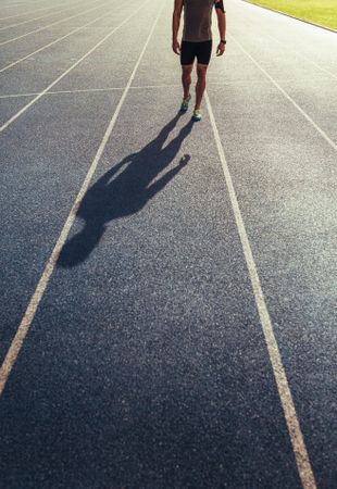 Legs of sprinter walking on running track