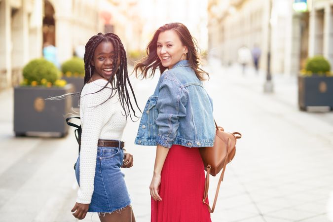 Female friends walking on an outdoor street and looking back