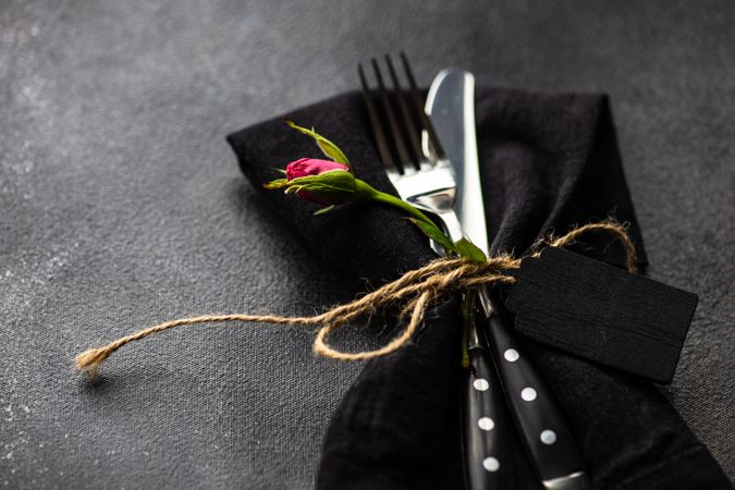 Silverware in matching napkin on counter with copy space and flower