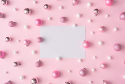 Different shades of pink and light-colored baubles on a pink background with paper card