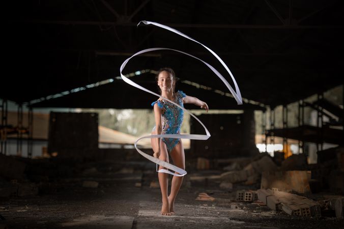Young girl performing rhythmic gymnastics exercises outdoors