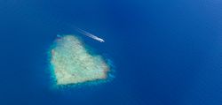Wide shot of island in the Maldives shot from an airplane, with boat
