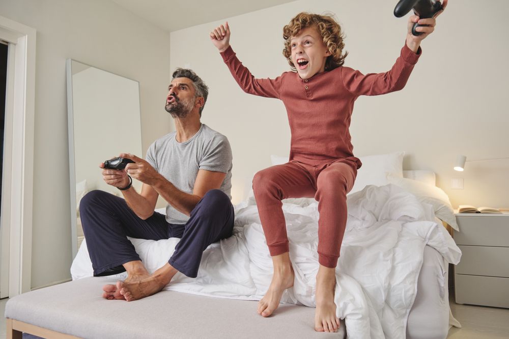Excited kid with father playing videogame
