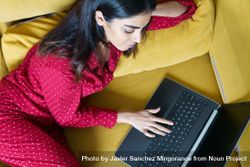 Female relaxing at home using laptop on yellow sofa 5wWLR5
