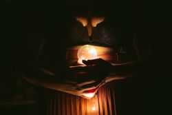 Faceless female with lightbulb in darkness