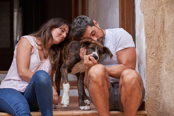 Happy couple petting dog on porch