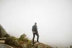 Anonymous man standing on cliff near countryside road