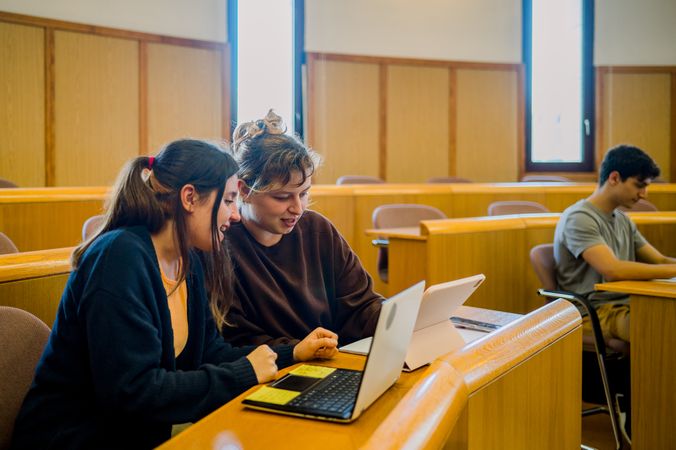 Team of woman students sitting at desk with laptop and tablet