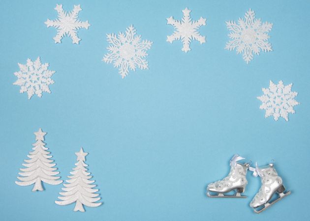 Winter flatlay with snowflakes and christmas tree ornaments on a blue background with space for copy