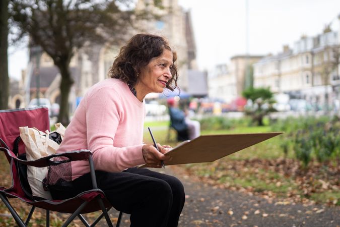 Smiling Indian woman in park with drawing board