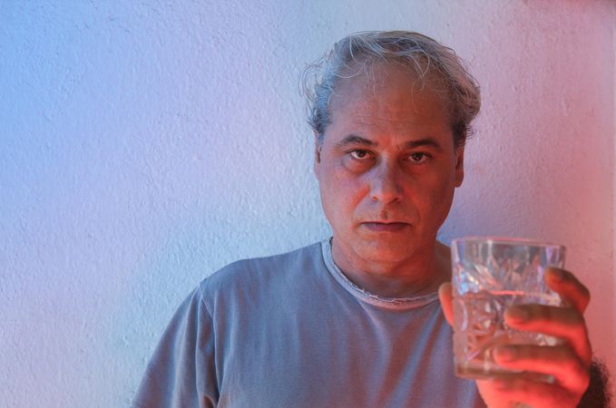 Middle aged in gray shirt holding a glass of water