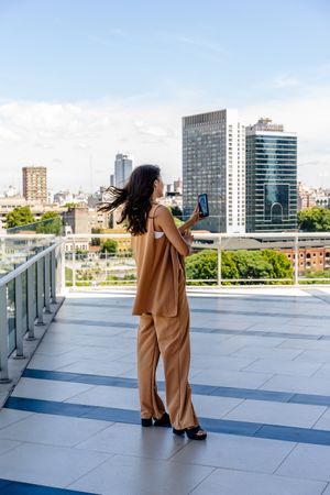 A rear view of a businesswoman is looking at her phone outdoors.