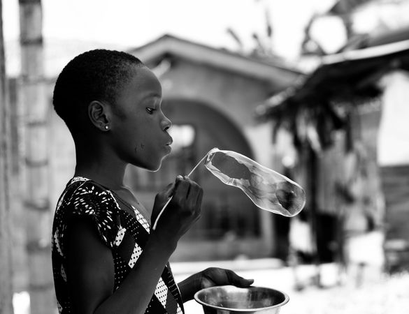 A young girl blowing a bubble in grayscale
