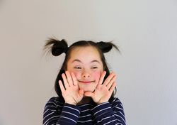 Playful child looking to the side with hands near her face