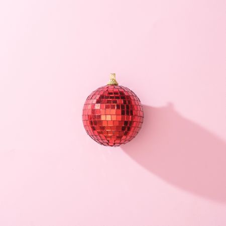 Red Christmas disco ball bauble on pink background with shadow