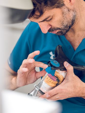 Bearded orthodontist examining denture casts in articulator