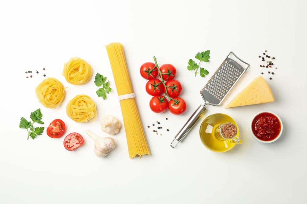 Composition with pasta and ingredients for cooking on plain background, top view