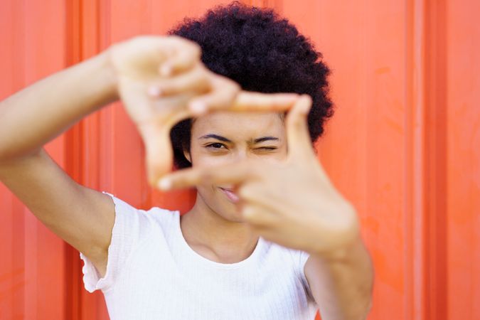 Woman looking through square frame made by her fingers