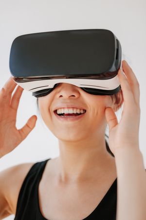 Close up shot of smiling woman using the VR goggles against grey background
