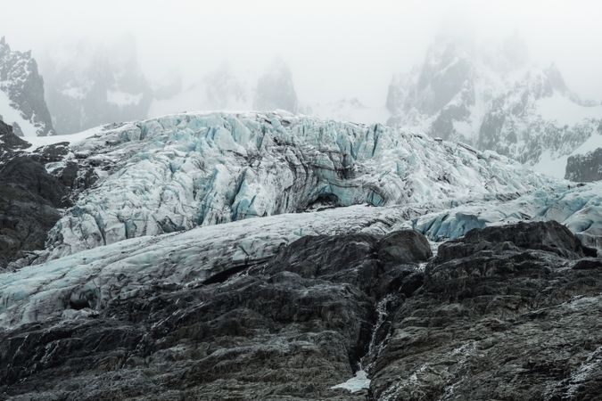 Gray rocky mountains with snow under foggy mist