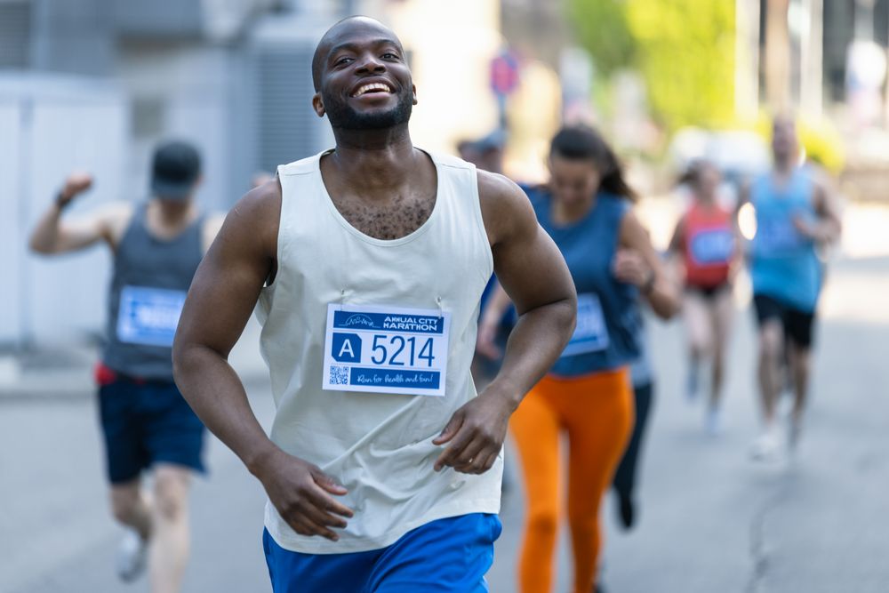 Portrait of Smiling Young Black Man Running in a City Marathon Celebrating Crossing the Finish Line in a Race
