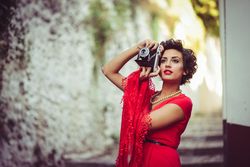 Elegant woman in dress and pearls taking a photo, copy space