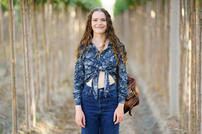 A Young Woman Dressed in a Beautiful Floral Top Walking Through Scenic Rows of Vines