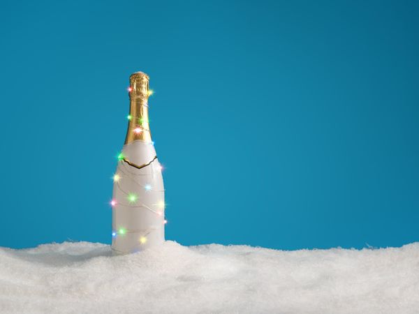Champagne bottle with lights, with snow on blue background
