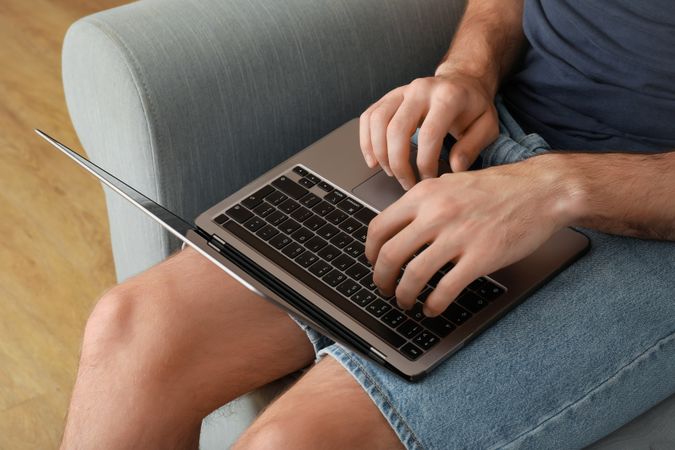 Young man working on laptop and sitting on sofa