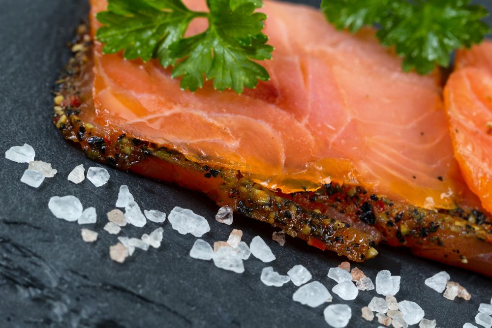 Smoked salmon slices and seasoning on natural stone background