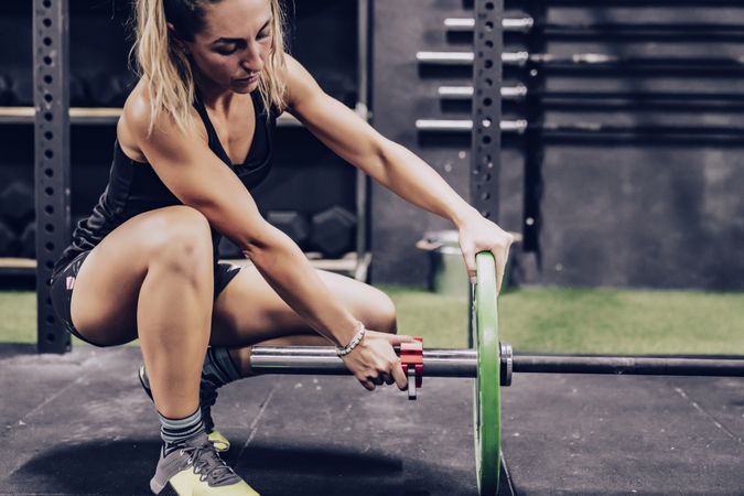 Concentrated female fixing barbell before workout