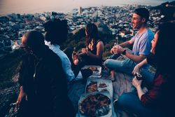 Group of friends eating pizza & drinking beers overlooking the city