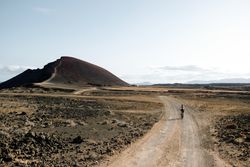 Back of female biking on Lanzarote dirt road towards hill