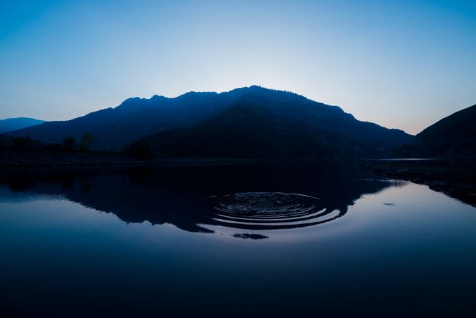 Picturesque view of water surface near amazing rock hills at sunset and blue sky