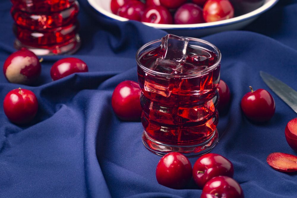 Red beverage near fresh fruits on cloth