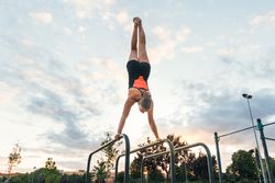 woman athlete doing handstand on parallel bars